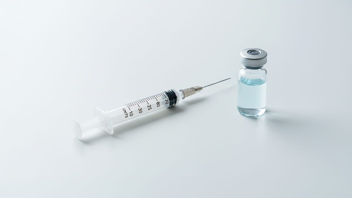 Illustration: An empty U-100 insulin syringe and a vial of pale blue liquid on a white surface.