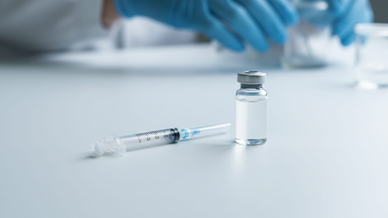 Illustration: An empty insulin syringe next to a sterile water vial on a white surface.