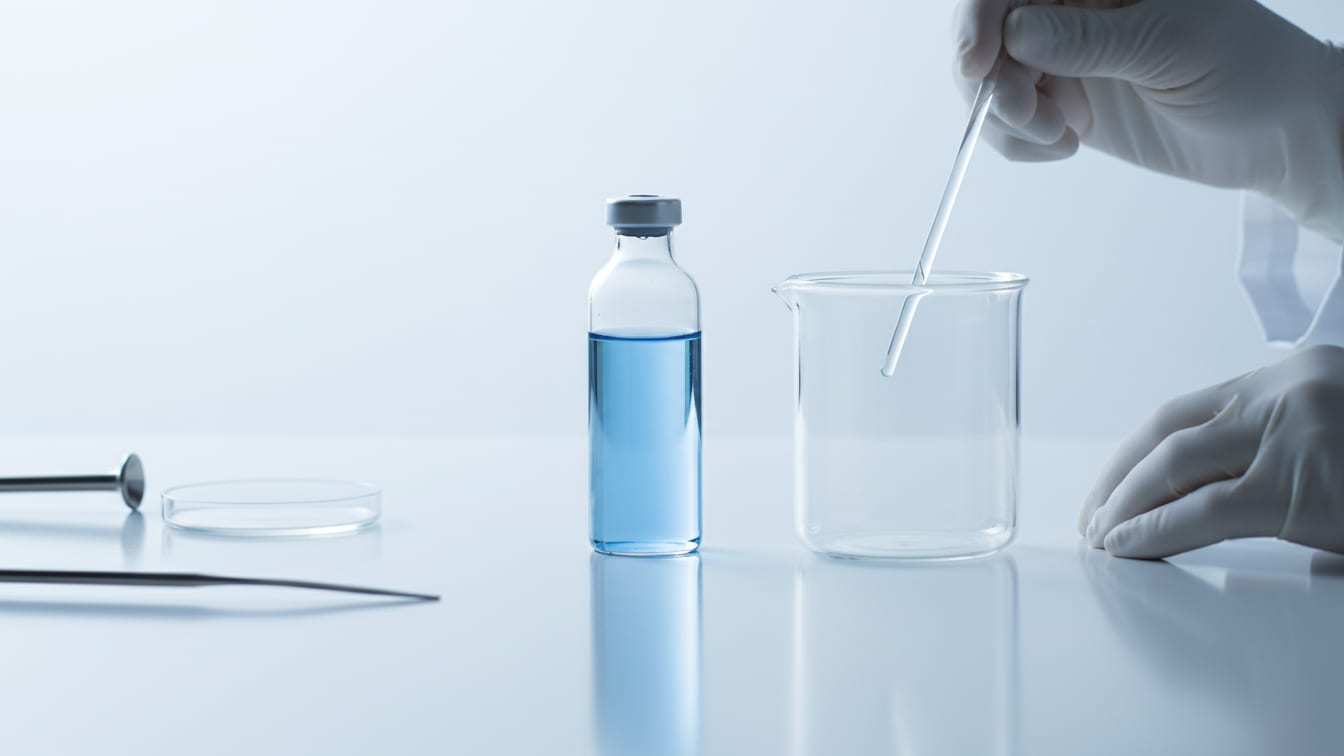 Illustration: Two clear glass vials on a white surface, one with pale blue liquid, one empty.